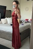 It's very classy. Very high quality material but it's a very dark rust. Darker than what's on the model. Maybe outside or with a flash it would look brighter but generally speaking, it's dark. I really love the collar. It gives it a modern fun twist. Fit is great. I'm 5'4 and wearing 3.5" heels and it comes to the floor. - Megan P.