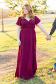 I ordered this dress in burgundy for my engagement shoot and it was perfect! The wrap creates a flattering shape and allows your leg to peak through a little when walking, but nothing crazy. The slit in the sleeves is not too noticeable and adds a bit of flare to the dress. Getting the dress on was a little difficult because of the way it ties, but it does have a snap on the chest to keep your boobs from flying out. It's a little bit sheer, but theres a small slip that covers from your waist to thighs underneath. The length was perfect with a small heel! I would totally recommend! (The color of the dress in the photos are slightly off due to the filter, in person it is a true burgundy.) - Sarah L.