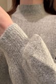 The material is really soft, softer than I expected, like a boucle consistency. VERY COZY like a blanket. The sweater is really cute on! I like the neckline, the sleeve cuffs, and how I can wear it long (hits a few inches below waist) or tuck it up for a more crop fitted look. The body is quite roomy as shown on the mode. It's a loose fit, but I would not go down a size. I ordered my typical size. Excited to wear it! - Katy M.