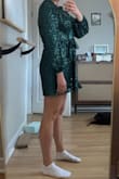 I was a little nervous ordering this dress because it's definitely on the short side, but I'm actually really happy with it. The green sparkly fabric is gorgeous in person. It catches the light beautifully without looking cheap or overly glittery. It feels like the perfect statement piece for a night out or a party. Length wise, it's very short, but it technically passes the sit test for me. My bare bottom doesn't touch the seat when I sit down. That said, I personally felt more comfortable wearing bike shorts underneath. They don't show at all, which made it easy to move around without worrying. I also tried on the square neck version, but I ended up preferring this wrap style. The wrap cut is just a little bit longer and gives a bit more coverage, which made a noticeable difference. It's still flirty and fitted, but slightly more practical. Overall, if you're okay with a mini dress and want something sparkly and fun, this one is a great pick. Just keep in mind the length and consider shorts underneath. - Erin K.