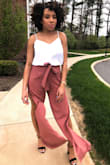 I bought these for a graduation and I received so many compliments! I wore them high waisted and I had some space but I tied them tight. The tie is a really cute touch! If you're curvy, I would not go down a size because the pants fit my thighs, butt, and hips perfectly and you want to be comfortable. The pants look really good with a cami tucked in. It would probably look really cute with a crop top as well. 
If you're my height, plan to wear these with heels because they are very long and you'll risk ruining the bottom of the pants if they drag. - Amber J.