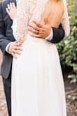 To all those long-legged women out there! To make this dress work, I had to add a quarter of an inch to the length. I had a professional remove the original seems to let out the dress at the bottom. I also wore NO shoes my entire wedding day because 1) I hate shoes and 2) The handsome love of my life is 5'7" on a good day.
The dress lightly skimmed the ground so I was able to go ham on the dance floor the entire night without tripping. My toes peeked from under the solid white piece, but the sheer material on top was longer and hid them a tad. I only wore this dress for my bridal party photos, first look and reception. I wore my grandmothers gown down the aisle. So if a train down the aisle is important to you and you are tall like me this is not the dress for you. Great to party in though!
It did gape at my sides when I lifted my arms out to my sides but that's because of how the dress is designed. So if you are on the bustier side, I would be mindful of this (don't want to give eveyone a show). I had to wear a sticky strapless/backless bra. My now hubby loved the back, just the right amount for a girl who wants to show skin, but is usually on the more modest side.
The length of the sleeves was perfect for my long arms. Just passed my bony wrists and layed elegently on my hand.
Everyone was amazed and could not believe how inexpensive my dress was (a major reason I purchased it since I was a bride on a budget)! It also photographs beautifully. Super white and stunning. - Jessie D.