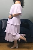 I purchased this dress for a friend's wedding. I'm a US size 12 and ordered the XL. Because the waist band is elastic, I will exchange for a smaller size. I was worried that the tiered ruffles would be unflattering on my hourglass figure; however, after trying-on I think it looks fine. This dress is so fun. I can't wait to dance the night away in it. - MEAGAN C.