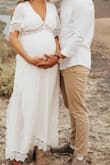 Ordered this dress for my maternity shoot in a M (not pregnant I am a S) and absolutely loved it! It worked out perfectly and fit better than I expected. The dress was not at all see through and wasn't too tight on my 34 week belly. The fabric doesn't have stretch to it, but sizing up 1 size worked perfect. - Bonnie C.