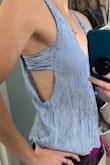 Would recommend ordering a size up if you want it to fit like the picture. I ordered a small, and it isn't as loose fiiting as the picture. The side strap is sewn into the side, so you cant adjust the tightness or height of that strap. It ties in the back but mostly just for show. The shirt is also shorter than I expected in the back. 
I washed it but hung it dry so it wouldn't shrink. Should have ordered a medium! - Tiffany S.