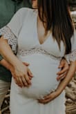 Beautiful high quality dress! This works as a maternity dress because the band is right below your bust! I am 5'0", 110lbs pre-pregnancy and was 140 lbs at 31 weeks pregnant for my pictures. For Lulus, I am usually a small for the chest and a medium for bottom because I'm curvy. I usually order dresses in medium to fit my butt and then have to tailor the top lol. For this dress (while pregnant), I ordered medium and large just in case. The medium fit great and zipped up very comfortably. Since I am short and my chest is smaller, I simply used a safety pin to hold the excess fabric behind my neck to avoid excessive cleavage. Highly recommend!! - Scarlet S.