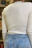 I love this shirt! It fits great, looks great on its own and works great with layering too. The material is quite different than what I expected, it is very tight and stretchy, and kind of stiff. The shirt looks too small when you first get it, but it stretches when you put it on. It is a little see through, and bra lines are very visible due to its tightness and material. The sleeves are a little long, but you can roll them and it still looks good. The body is a perfect length. The neck looks good folded down when worn on its own, or looks good up with layering. It's very warm and comfortable. - Erica G.